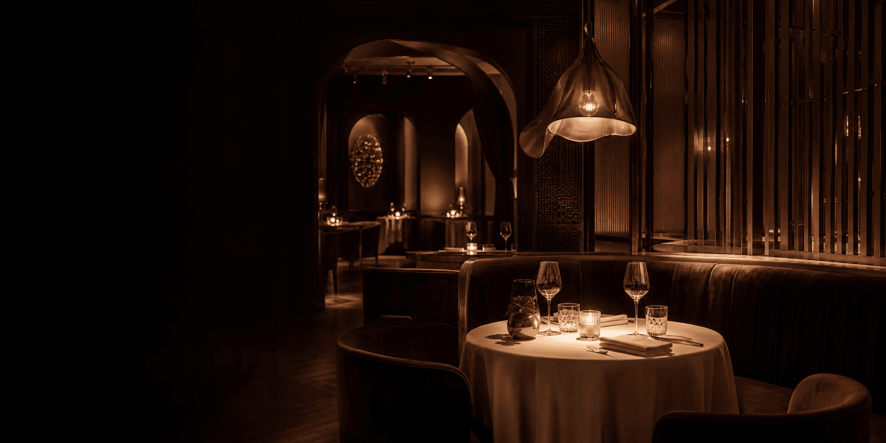 An intimate table set beneath warm pendant lights in a maroon dining room